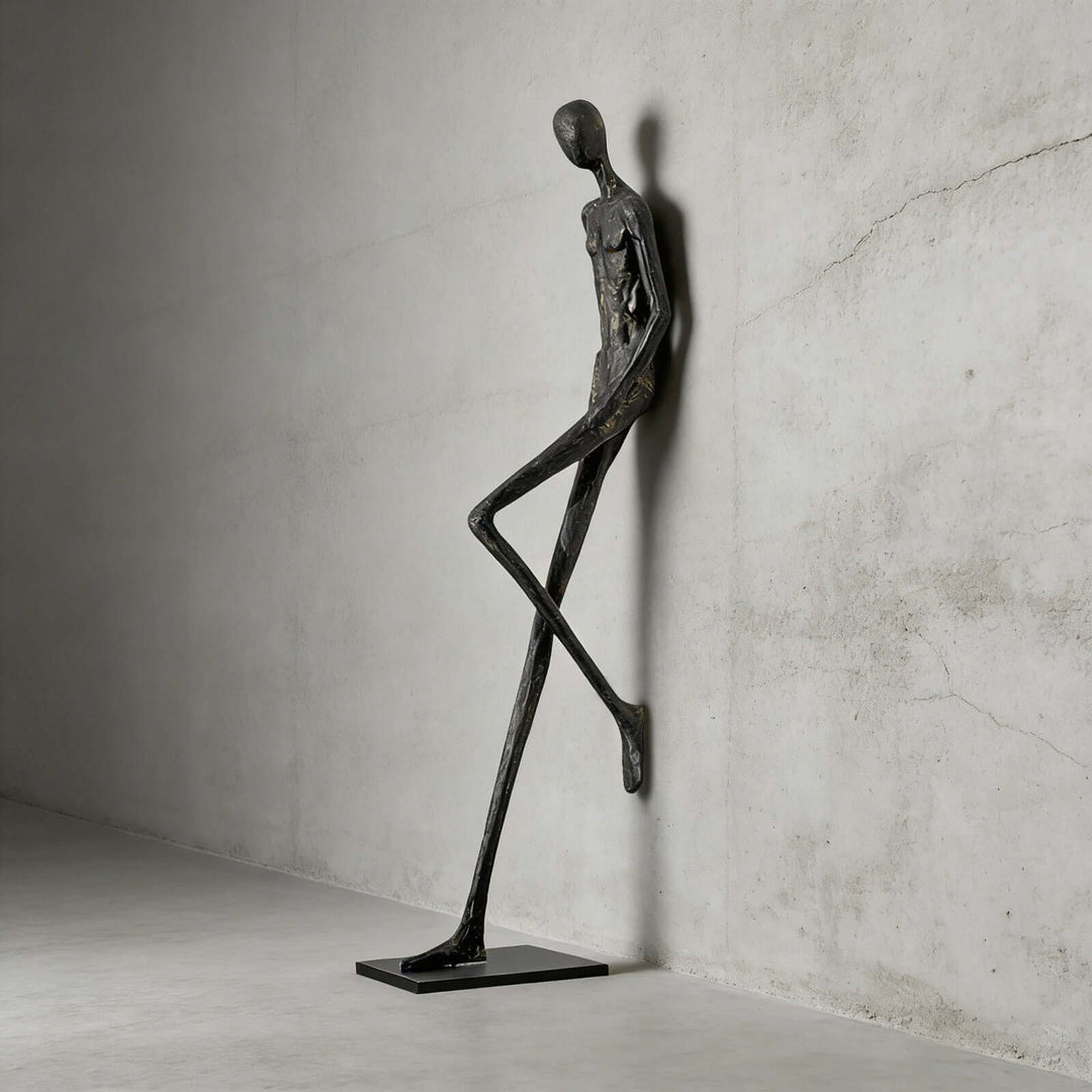 Black abstract Lemvix sculpture standing against a concrete wall.