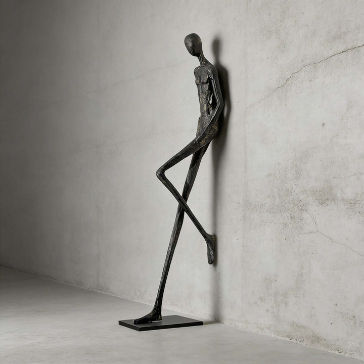 Black abstract Lemvix sculpture standing against a concrete wall.