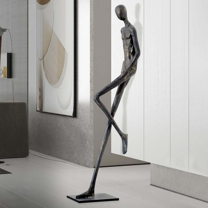 Close view of a black resin sculpture beside a corridor wall.