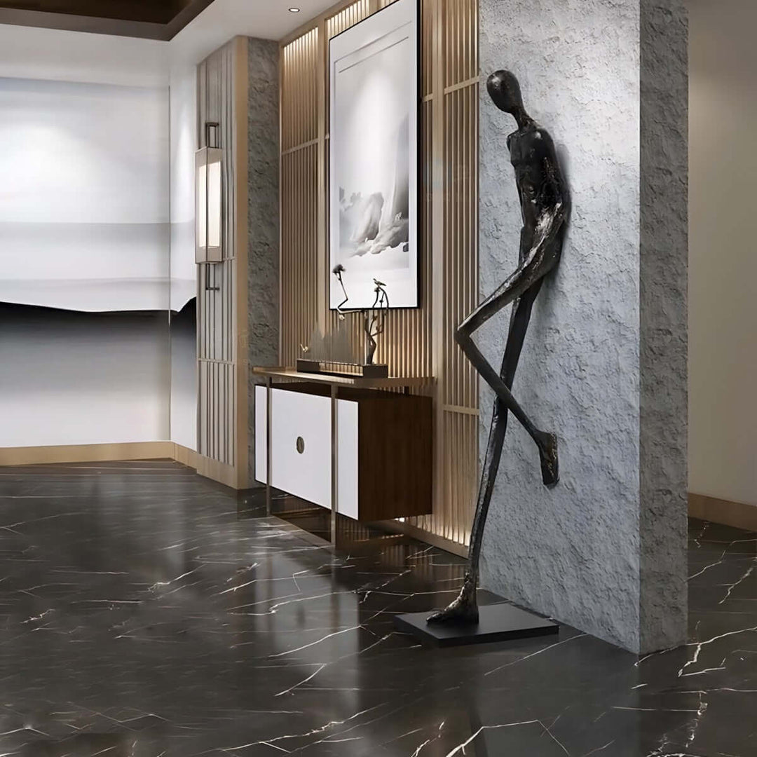 Black resin sculpture beside an entry console on a stone wall.