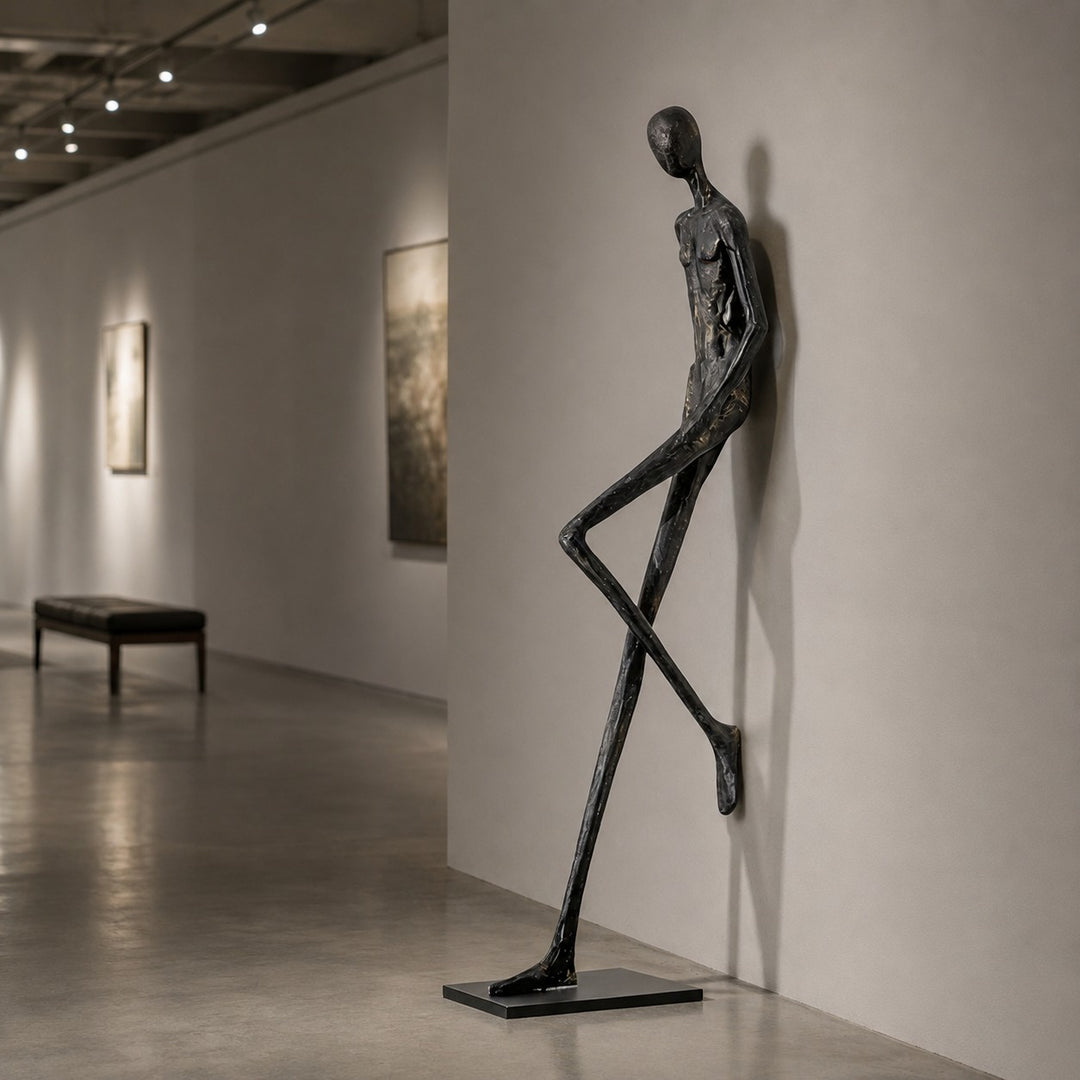 Black abstract sculpture leaning by a wall in a gallery-style hallway.