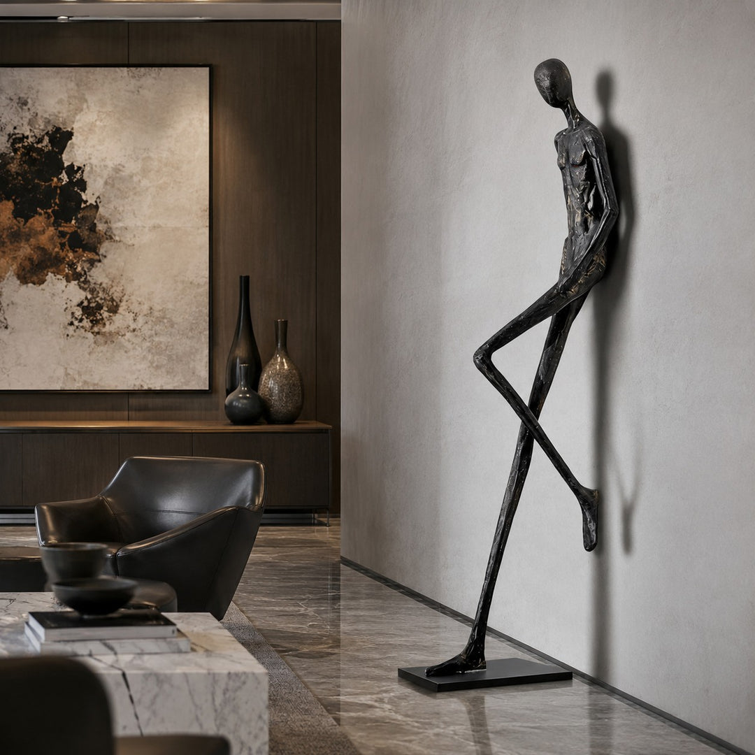 Tall black sculpture displayed in a lounge corner beside wall art.