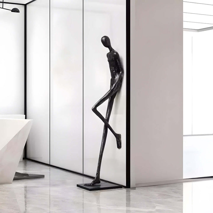 Black resin sculpture displayed against a white modern hallway wall.