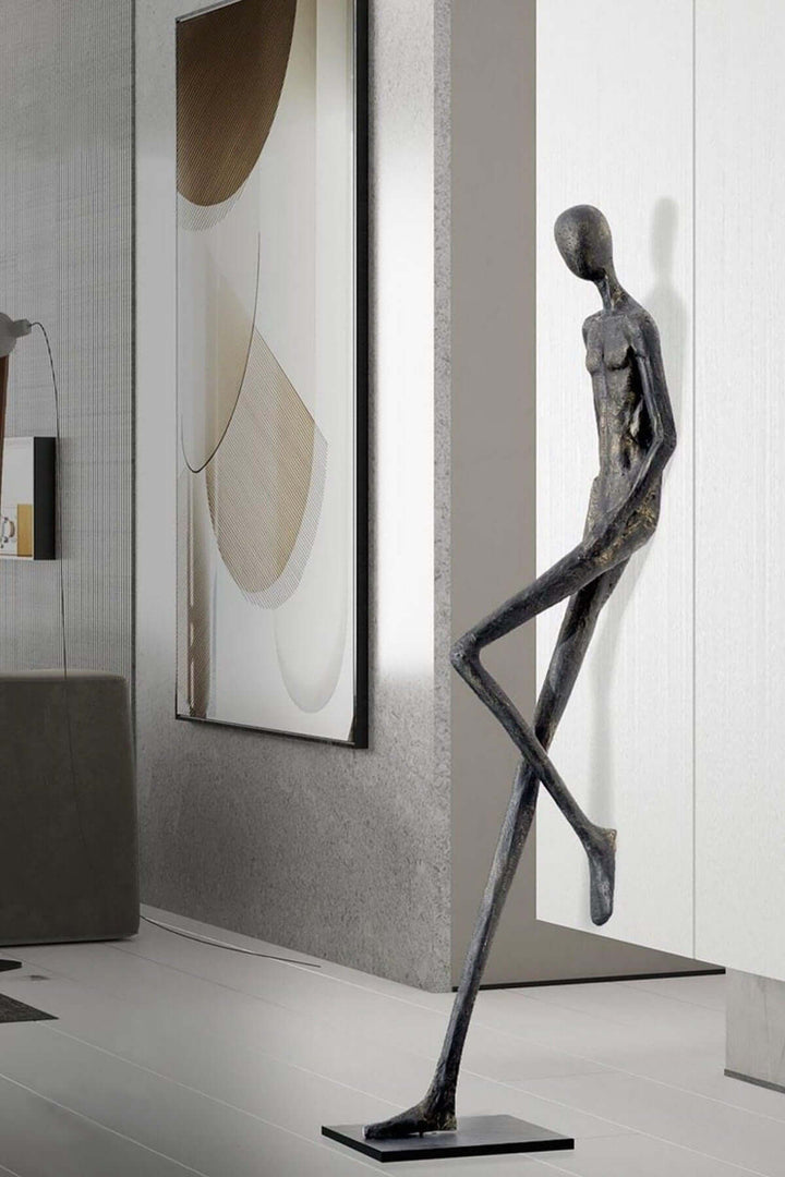 Black resin sculpture shown beside wall art in a narrow corridor.