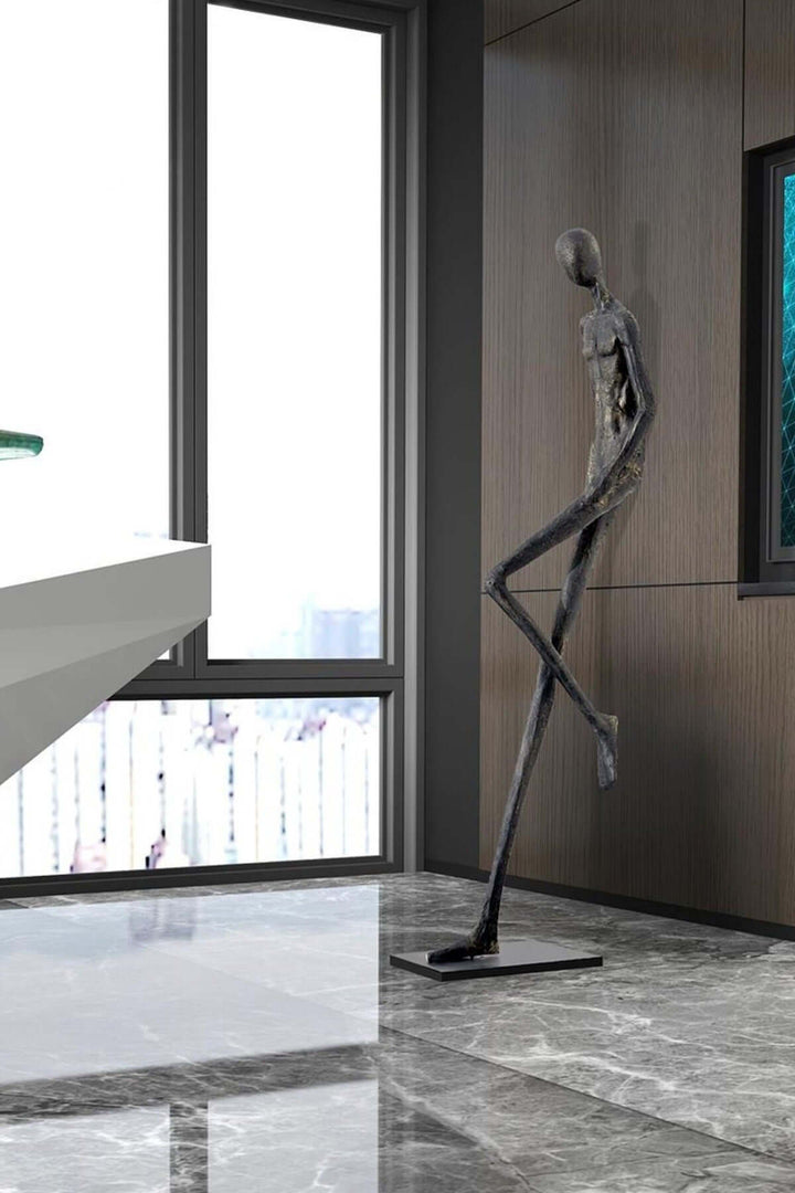 Black resin sculpture standing near a window in a modern hallway.