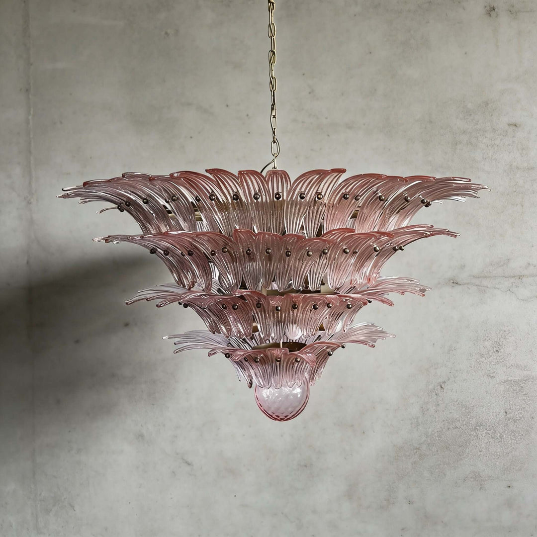 Pink glass Palmette chandelier shown in a large tiered studio view on a gray wall.
