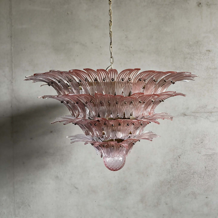 Pink glass Palmette chandelier shown in a large tiered studio view on a gray wall.
