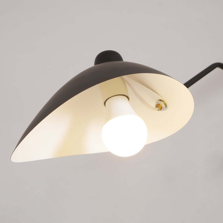 Close-up of a black cone shade and glowing bulb on the ceiling light.