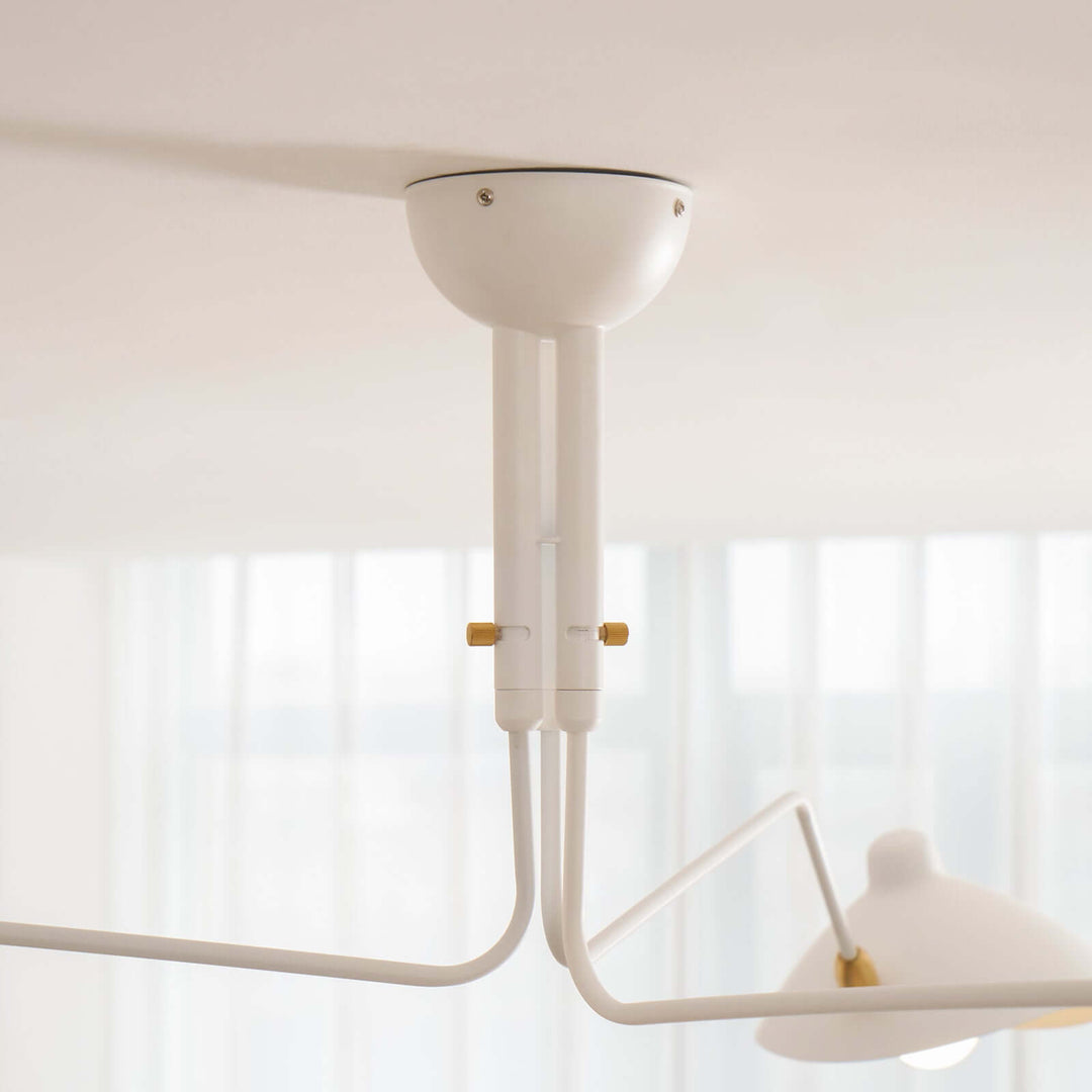 Close-up of the white ceiling stem and angled arms on the fixture.