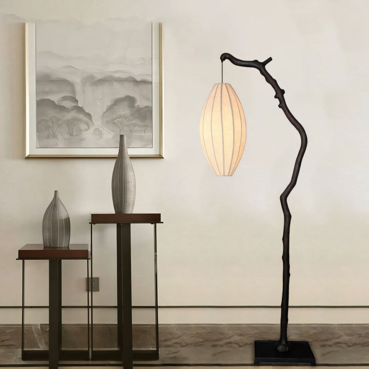 Black branch floor lamp glowing beside a console table and framed wall art.