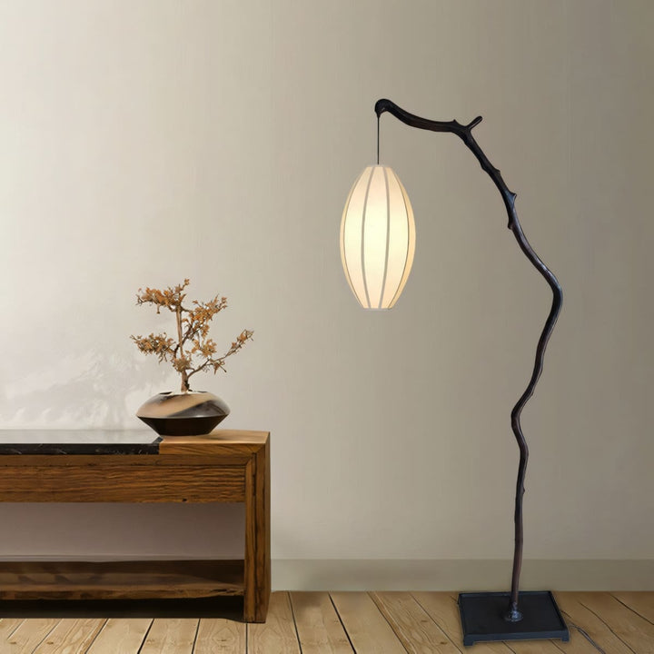 Tree floor lamp with an oval shade placed beside a low console table.