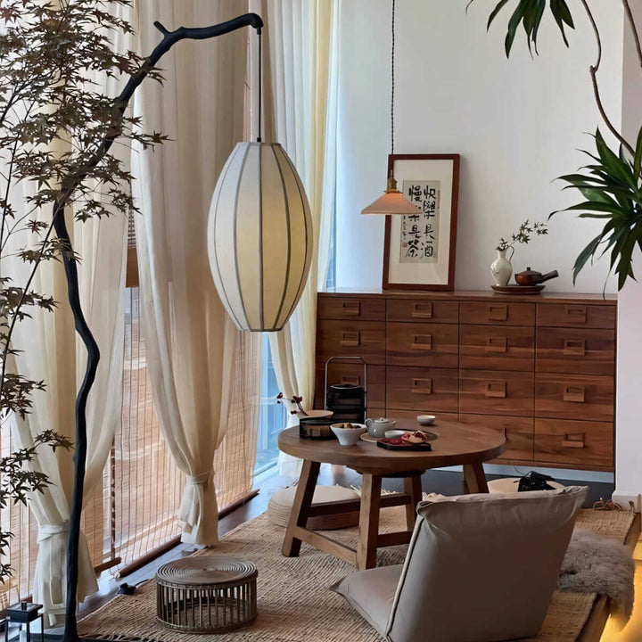 Tree branch floor lamp beside curtains and a wooden dresser in a living room.