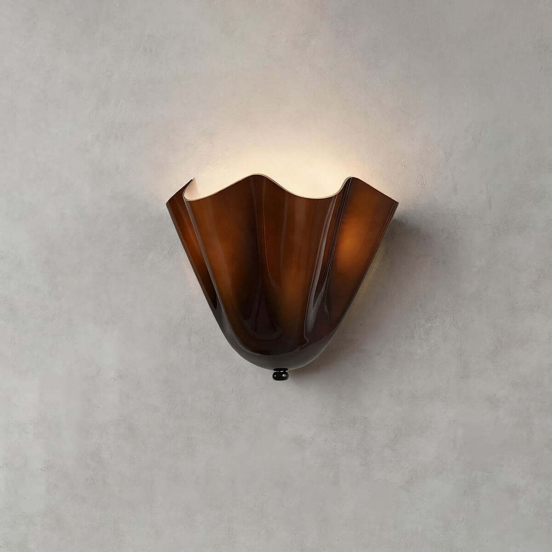 Amber glass wall sconce with black hardware shown unlit on a gray wall.