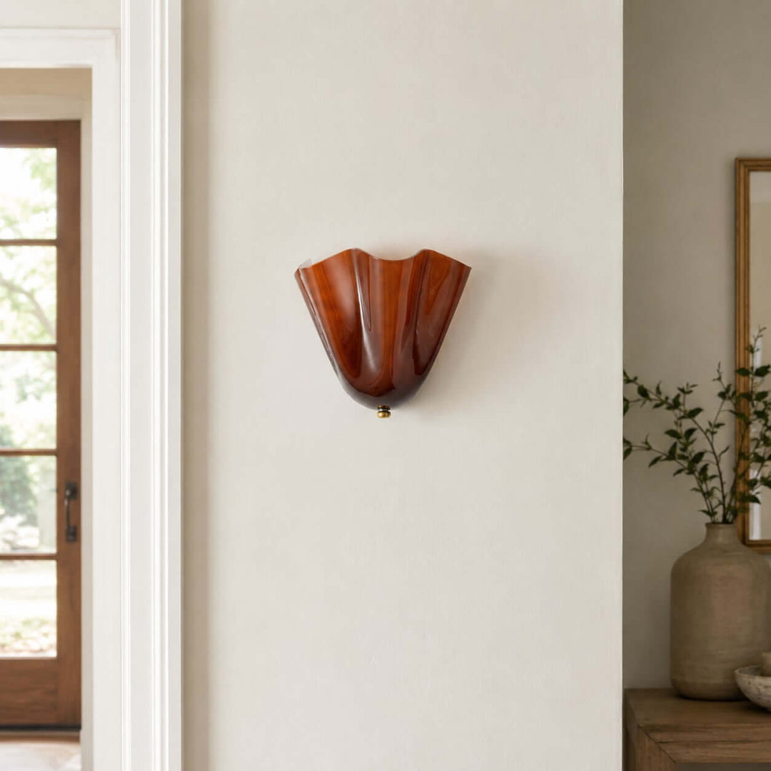 Amber fluted glass wall sconce mounted on a clean wall beside a doorway.