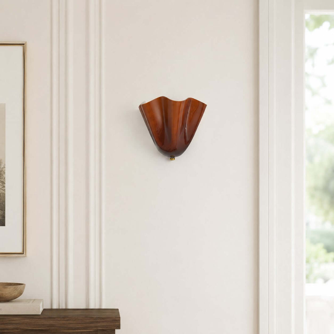 Amber glass wall sconce shown close on a pale wall near a doorway.