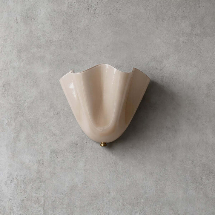 Beige fluted glass wall sconce shown unlit on a gray wall.