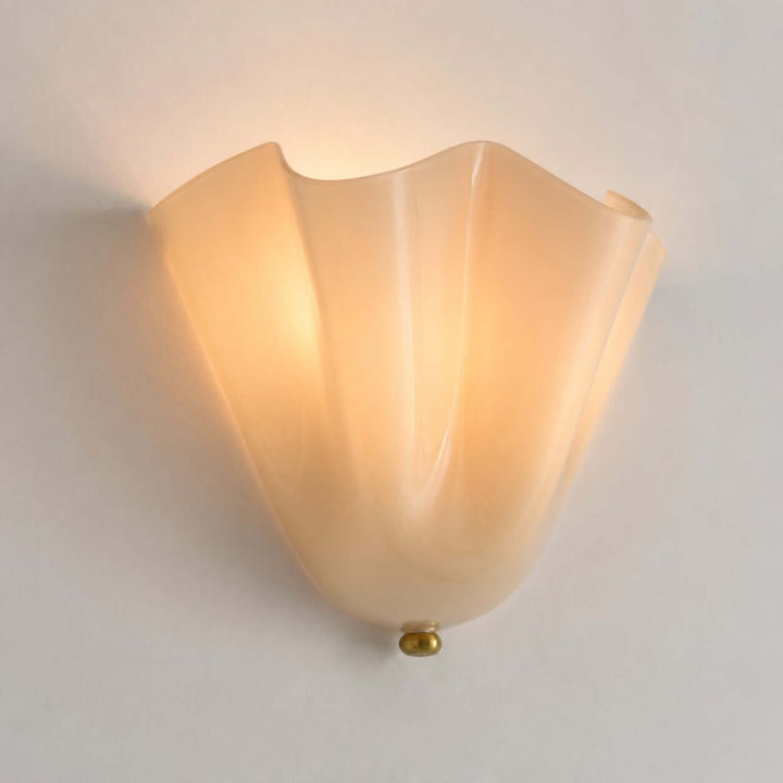 Beige fluted glass wall sconce lit on a light gray background.