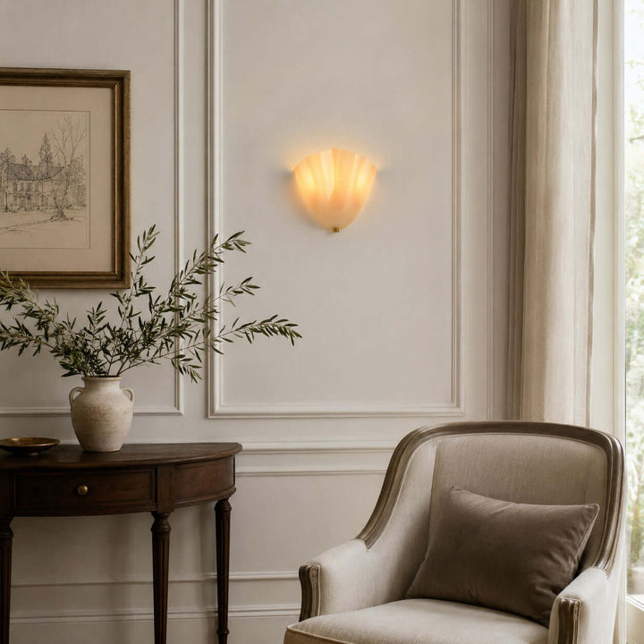 Amber glass wall sconce above an entry console with framed wall art.