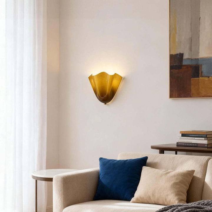 Green glass wall sconce above a sofa with framed artwork in the background.