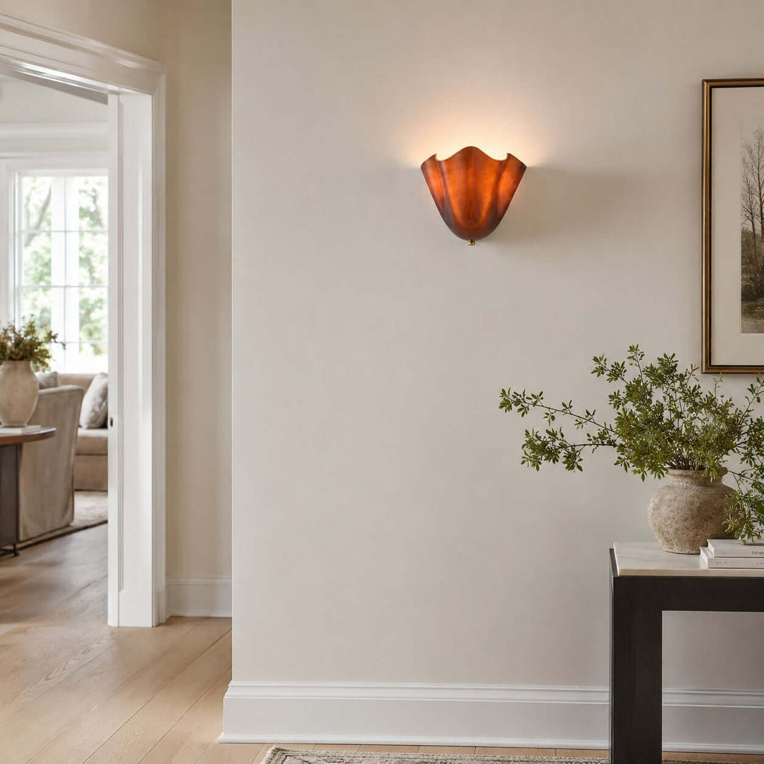 Amber glass wall sconce mounted near a doorway in a bright hallway.
