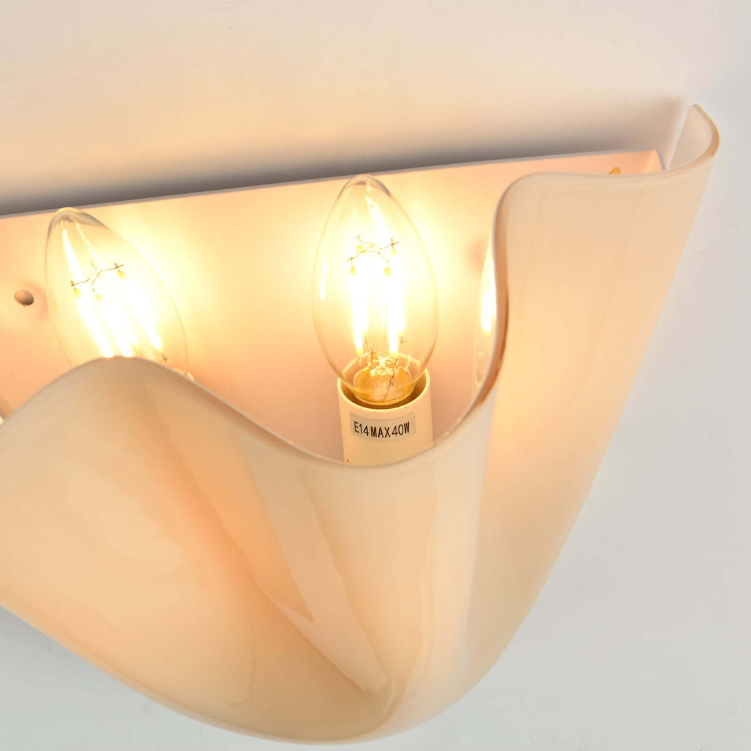 Close-up inside the fluted glass wall sconce showing the lamp socket and warm bulb.