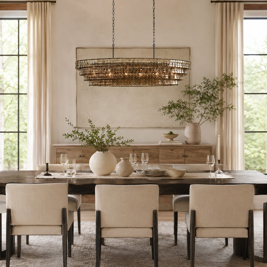 Gold tone round glass chandelier above a dining table in a bright room.