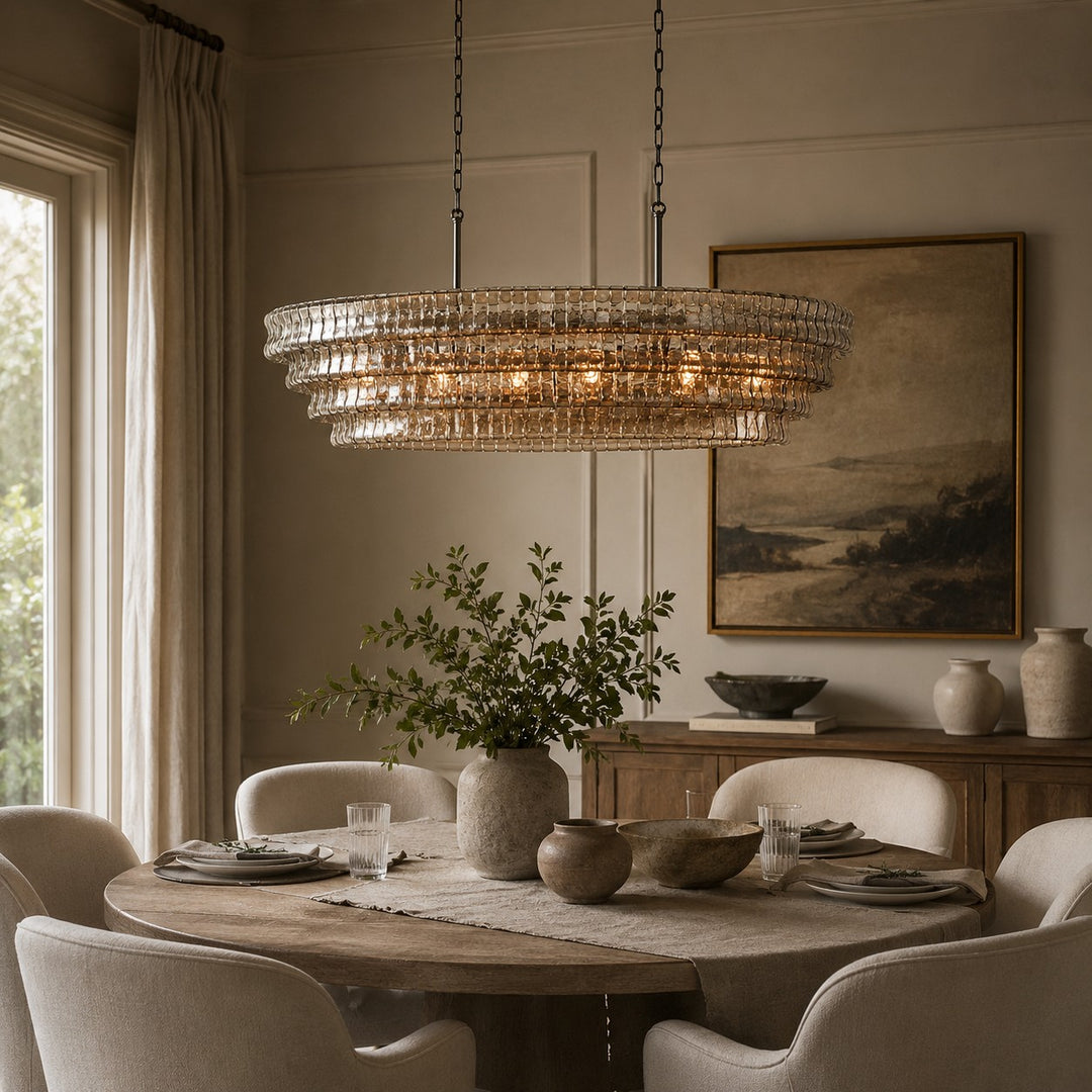 Round glass chandelier over a dining table with framed wall art behind it.