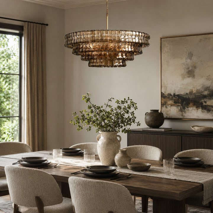 Layered round glass chandelier shown above a set dining table near a window.
