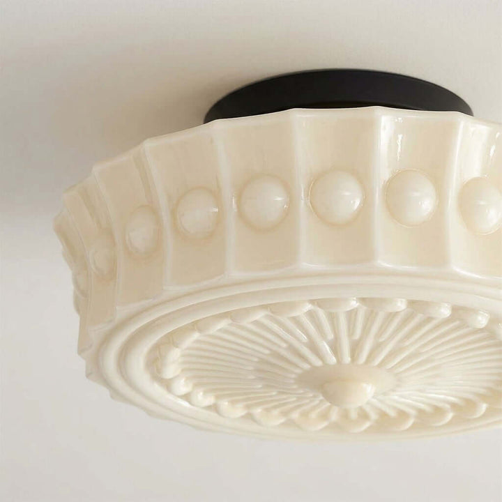Close-up of art deco floral and circular relief patterns on the creamy glass ceiling shade