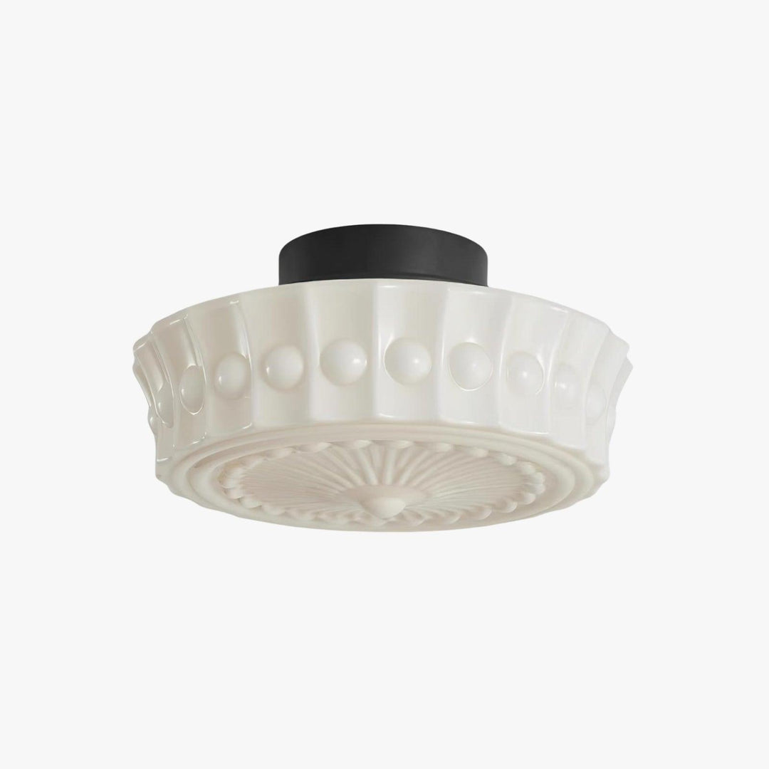Front view of a creamy milk glass flush mount ceiling light with art deco floral pattern