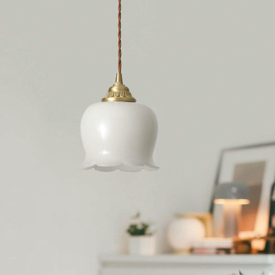 Vintage hanging light with a white flower shade and antique brass cap in a calm neutral interior