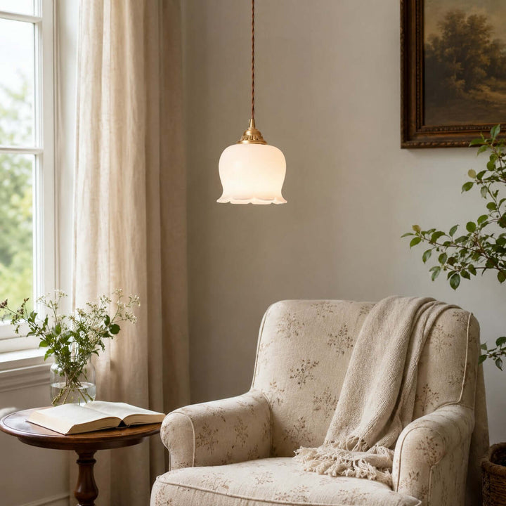 Vintage flower pendant light with a warm glow above a cozy reading chair by the window