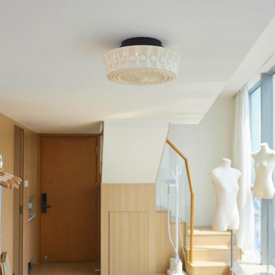 Round white glass flush mount ceiling light installed in a modern foyer beside a staircase