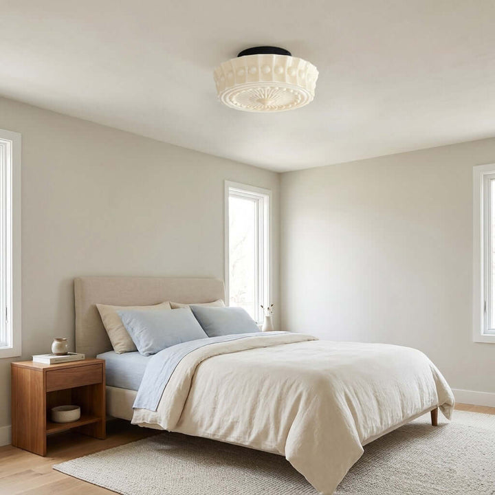 White milk glass flush mount ceiling light in a bright bedroom with natural wood furniture
