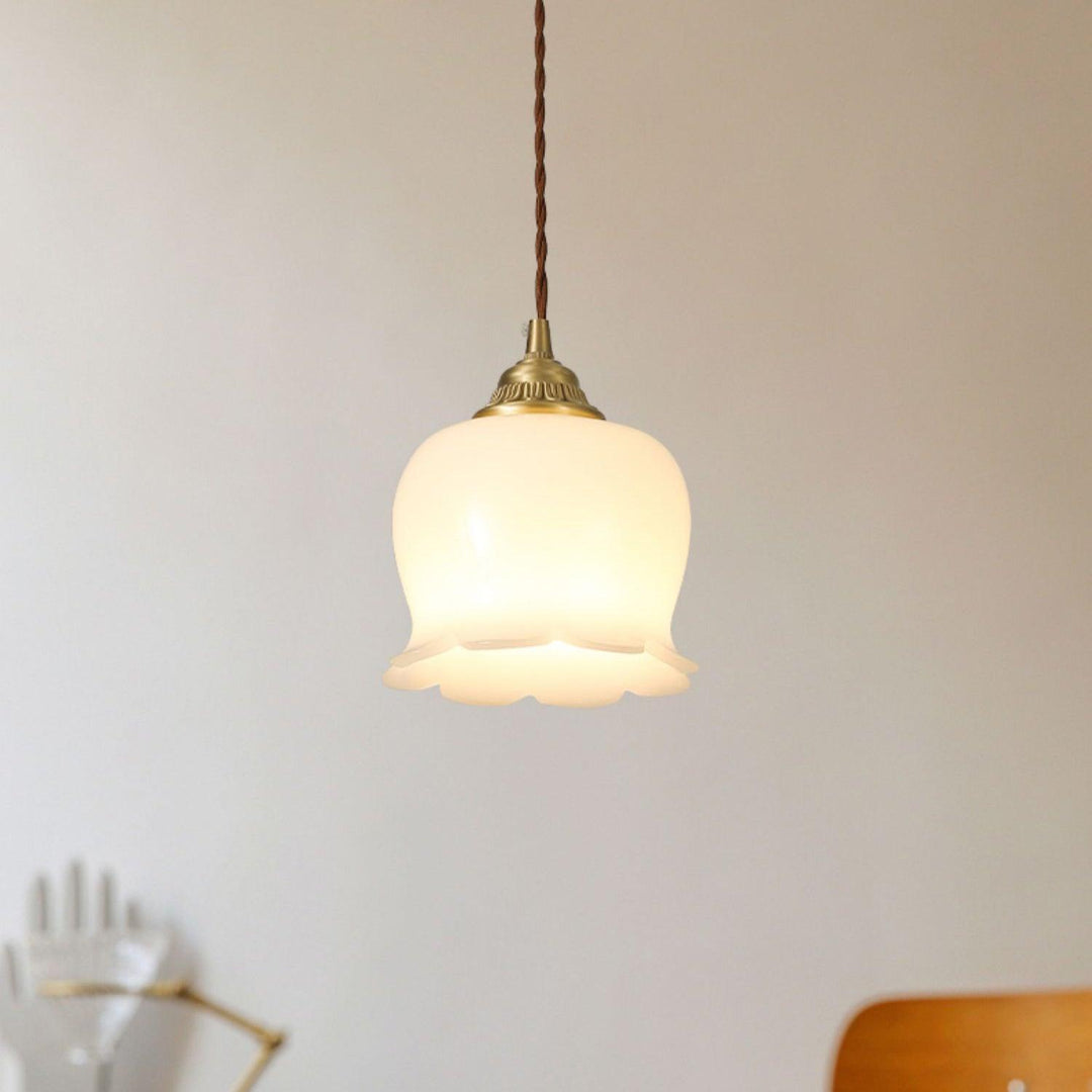 Warm hanging pendant lamp with a scalloped flower shade and antique brass fitting