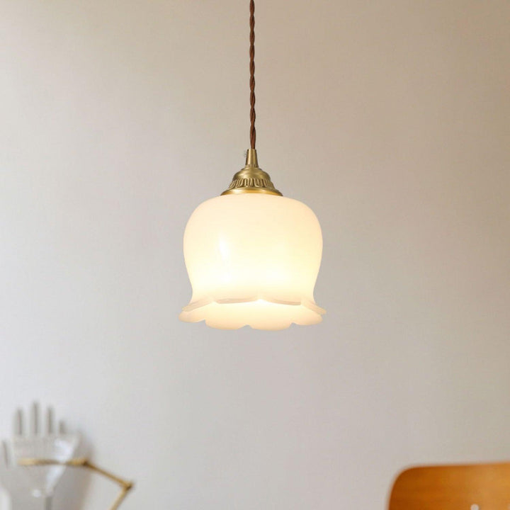 Warm hanging pendant lamp with a scalloped flower shade and antique brass fitting