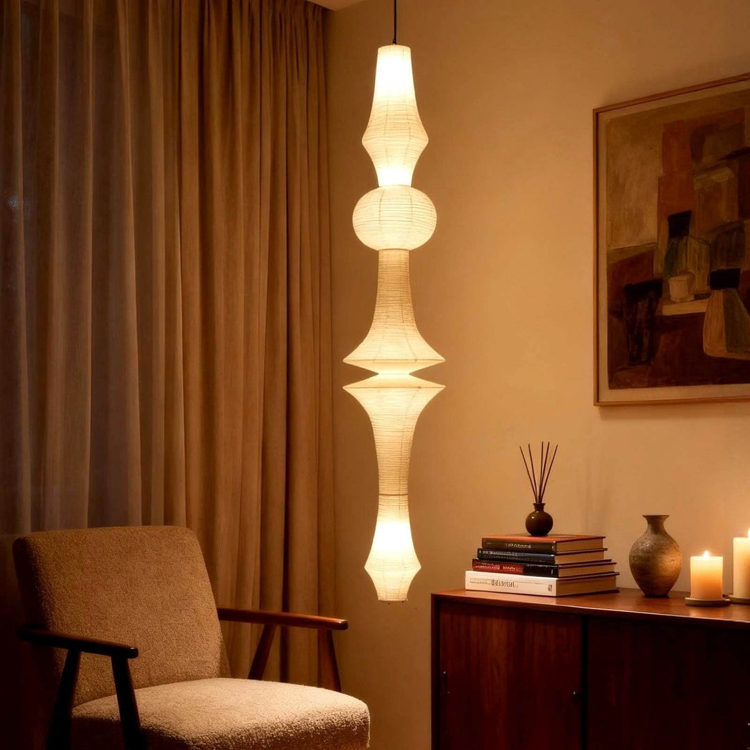 Tall Washi paper pendant light casting a warm glow beside an armchair and wood sideboard in a reading nook