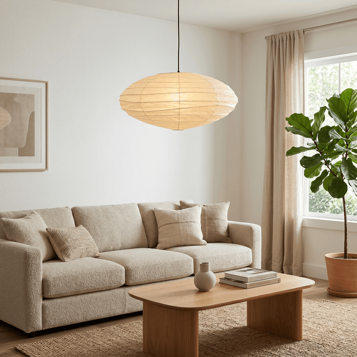 Washi paper pendant light above a sofa in a warm neutral living room.