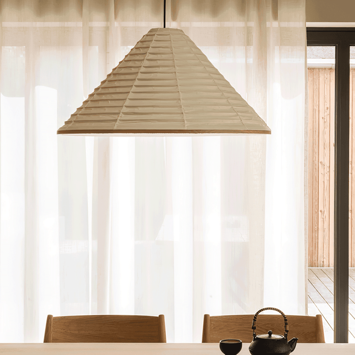Oversized Washi paper pendant lamp above a wood dining table styled with a black teapot