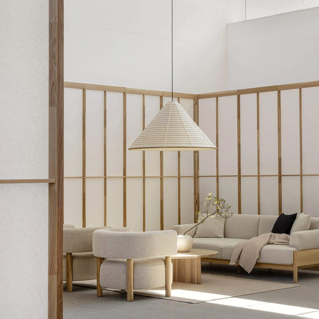 Washi paper pendant light above a round coffee table in a softly furnished Japandi living room
