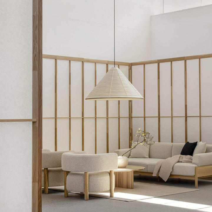 Washi paper pendant light above a round coffee table in a softly furnished Japandi living room