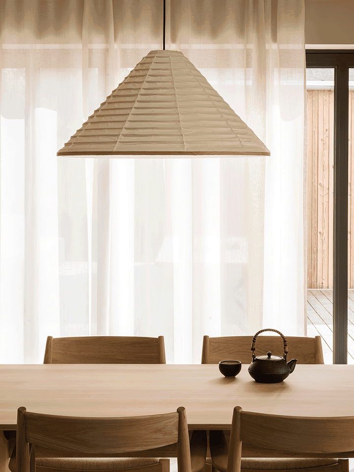 Large Washi paper pendant lamp above a minimalist wood dining table with a traditional black teapot