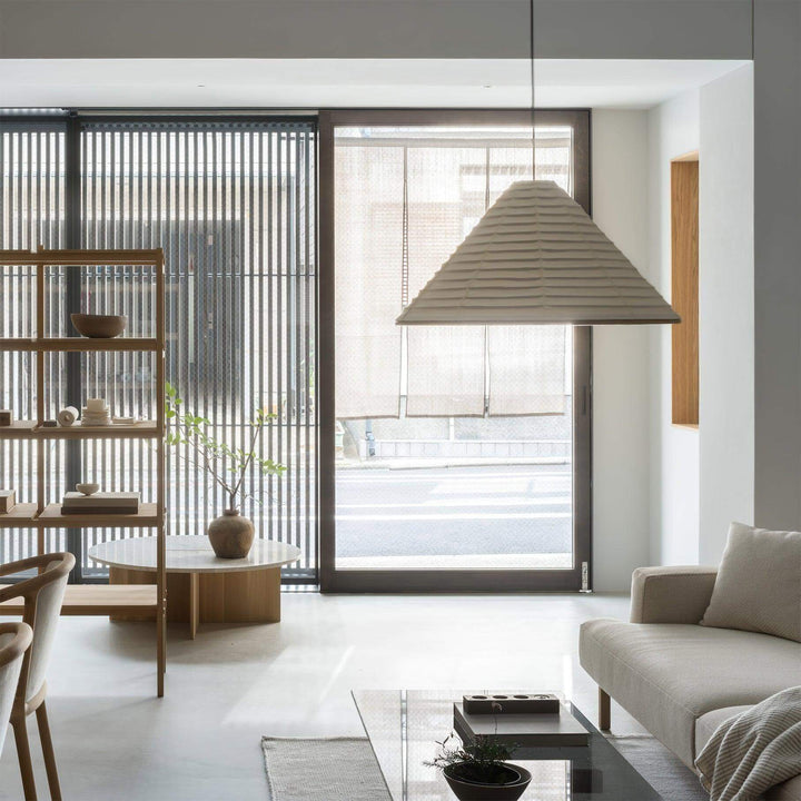 Large Washi paper cone pendant lamp in a minimalist living room with wood shelving and glass doors
