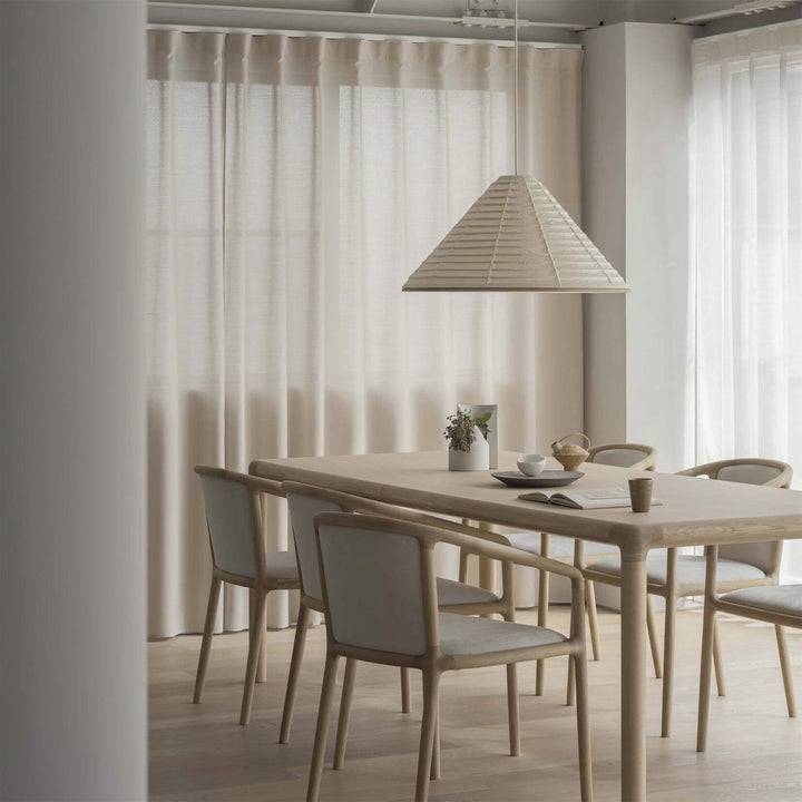 Washi paper cone pendant lamp above a light wood dining table in a bright neutral dining room
