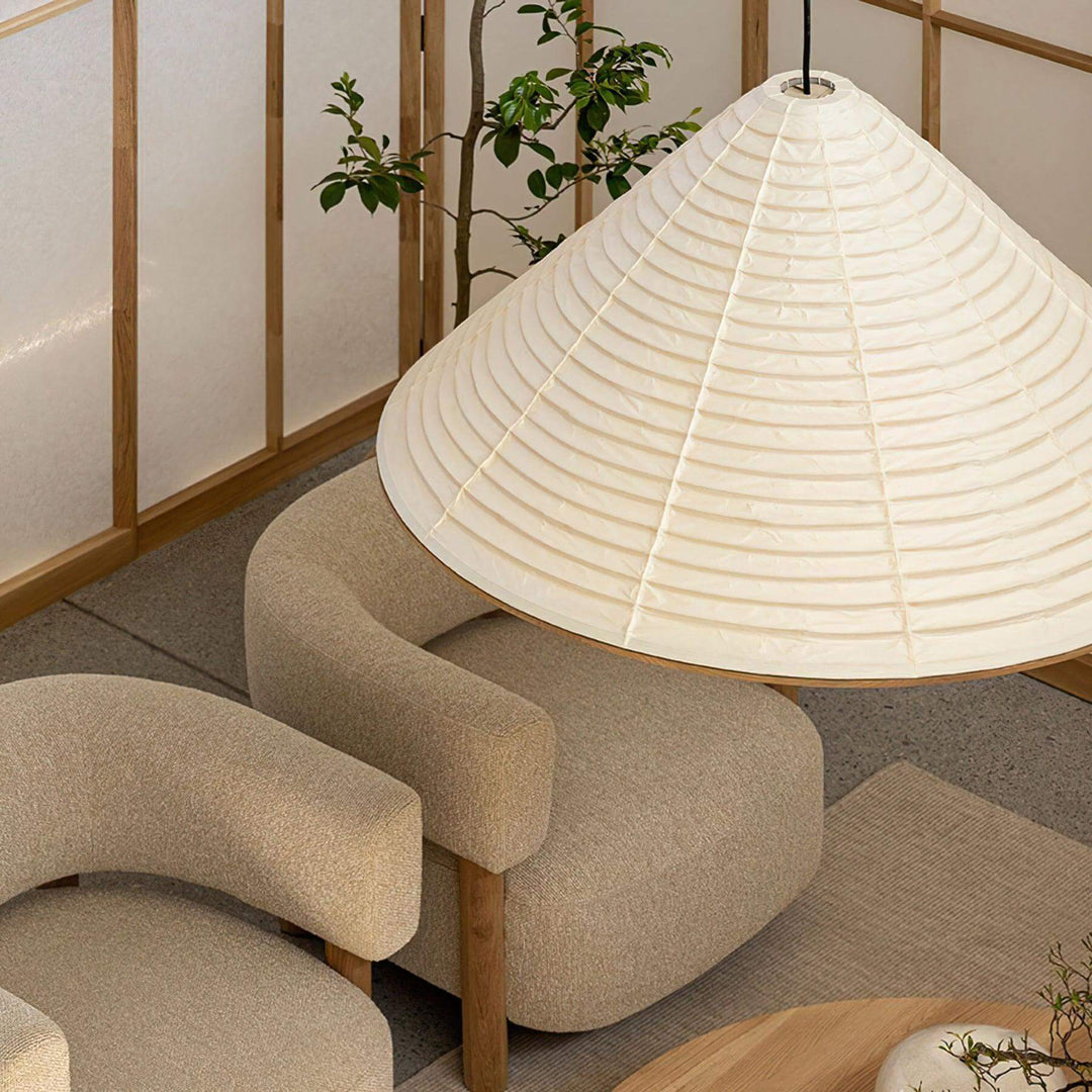 Close view of an oversized Washi paper cone pendant lamp suspended above neutral lounge chairs