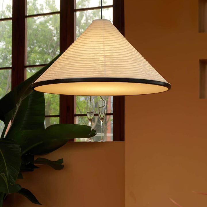 Close view of the illuminated Washi Paper Hat Pendant Lamp beside a window and tropical green plant
