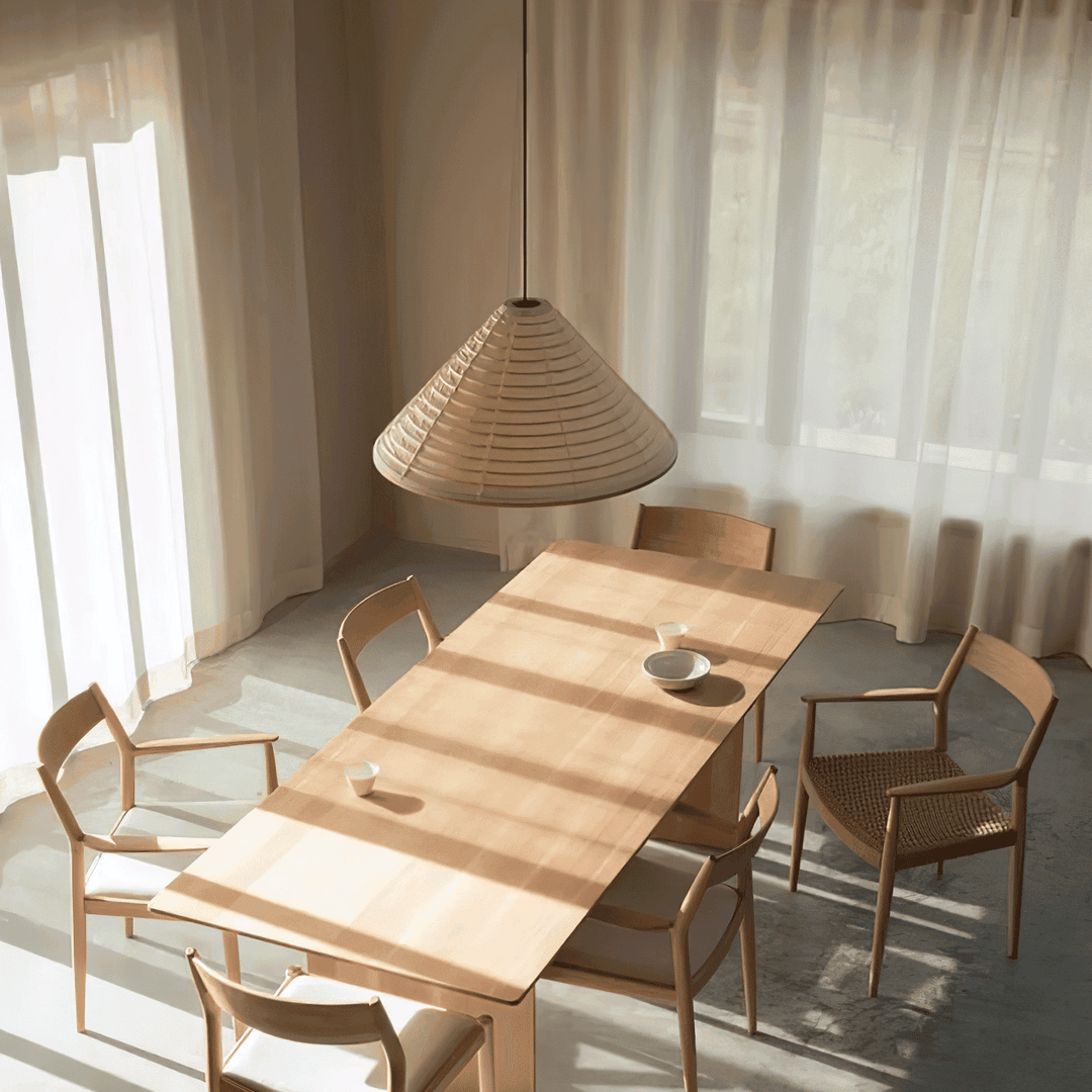 Washi paper pendant light viewed from above a sunlit wood dining table with natural chairs