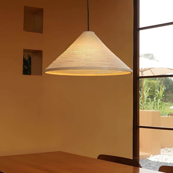 Washi paper pendant light casting a warm glow above a wood dining table beside a tall window