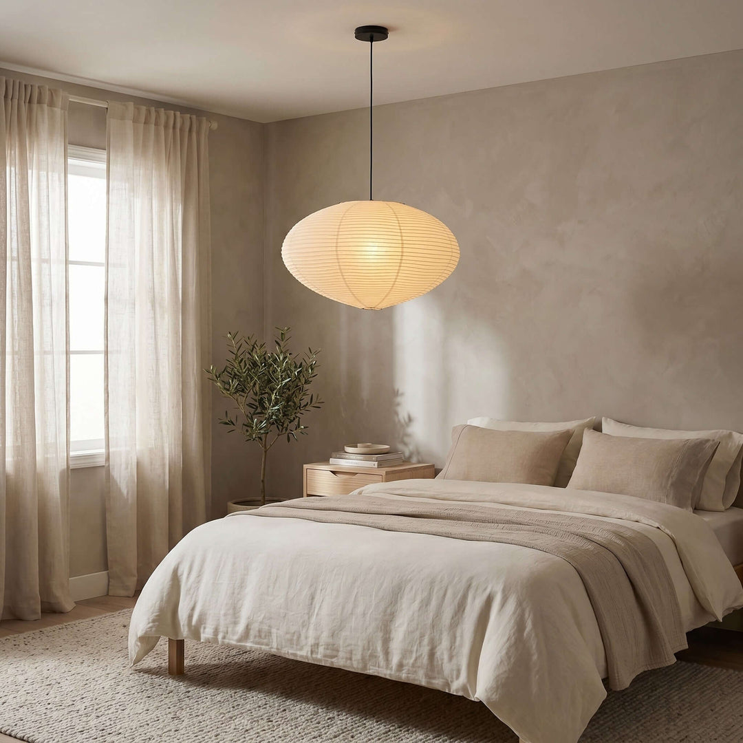 Washi paper pendant light with a black cord above a neutral bedroom.