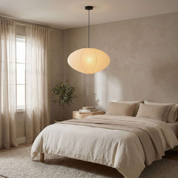 Washi paper pendant light with a black cord above a neutral bedroom.
